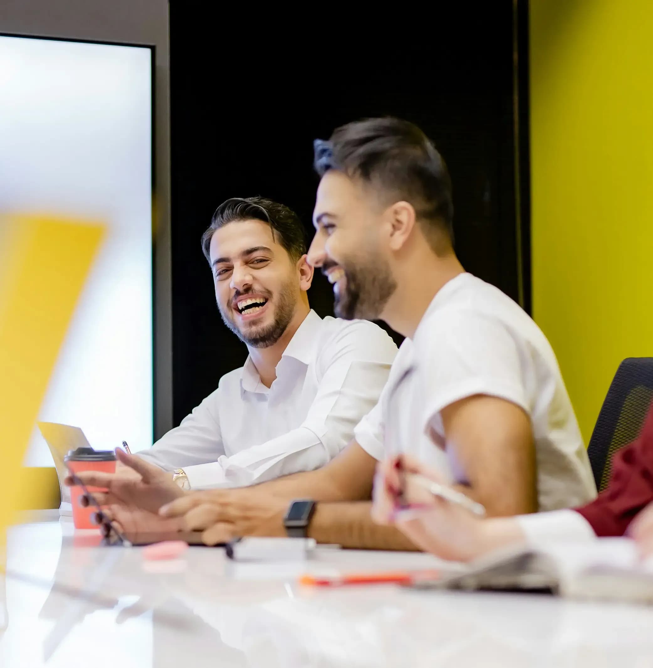 Colleagues smiling in an office environment with yellow color details